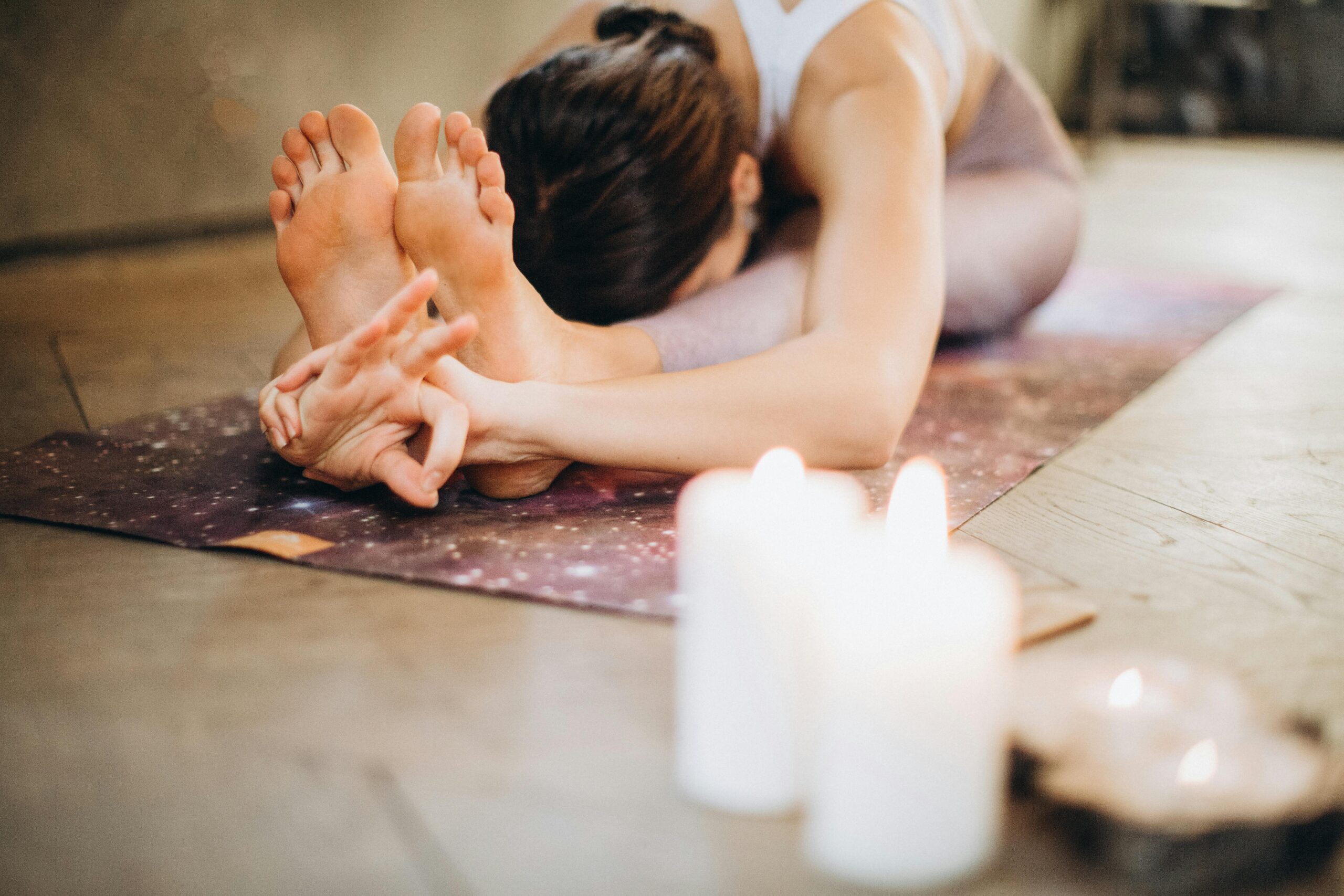 Home A woman performing yoga with candles, focusing on relaxation and mindfulness indoors.