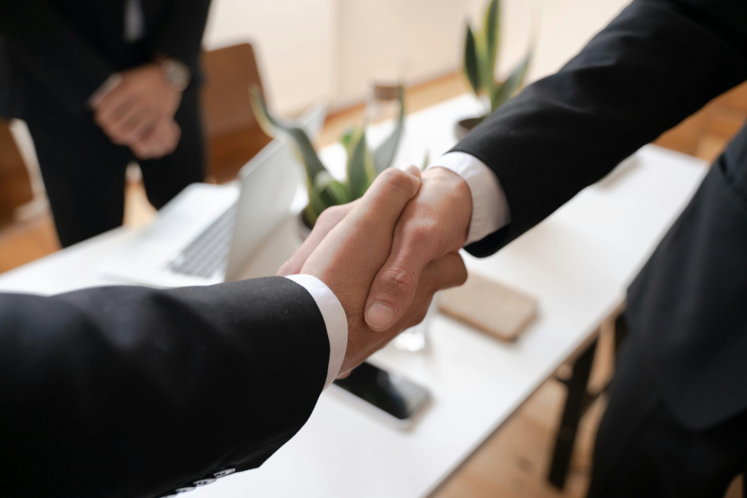 Home Close-up of a handshake between two professionals in a business setting, symbolizing agreement.